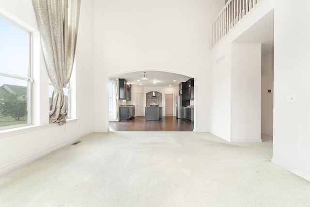 4215 Chandi Ct, Ypsilanti, MI 48197 - unfurnished living room featuring a towering ceiling, dark carpet, and arched walkways