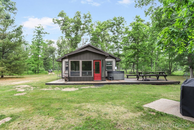 9228 S Star Lake Dr, Baldwin, MI 49304 - back of house featuring a hot tub, a wooden deck, board and batten siding, and a lawn