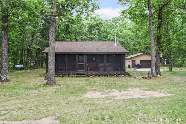 9210 S Star Lake Dr, Baldwin, MI 49304 - view of front facade with a sunroom, an outdoor structure, a detached garage, and a front lawn