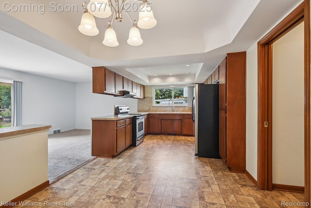 36819 Maas Dr, Sterling Heights, MI 48312 - kitchen with stainless steel appliances, a raised ceiling, light countertops, brown cabinetry, and a chandelier