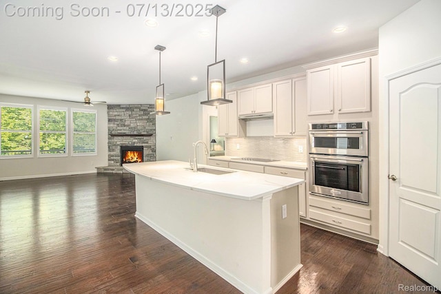 4104 Ashdale Way, Clarkston, MI 48348 - kitchen featuring double oven, a fireplace, backsplash, dark wood-style floors, and open floor plan