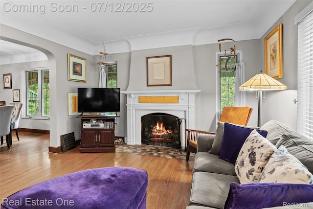 115 Illinois Ave, Pontiac, MI 48341 - living area with wood finished floors, arched walkways, and a fireplace with flush hearth
