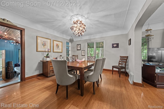 115 Illinois Ave, Pontiac, MI 48341 - dining room featuring light wood-style flooring, arched walkways, and a chandelier