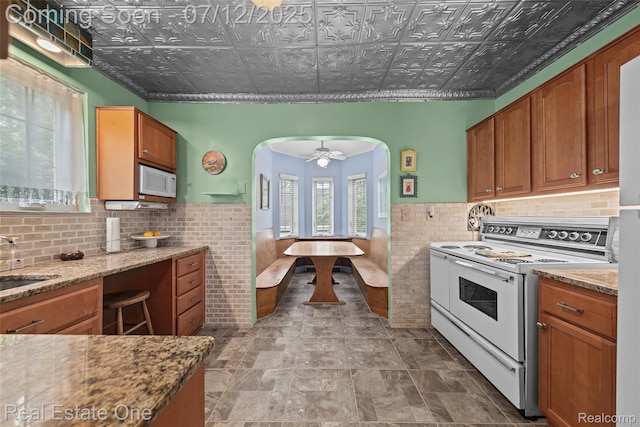 115 Illinois Ave, Pontiac, MI 48341 - kitchen with white appliances, tile walls, arched walkways, wainscoting, and an ornate ceiling