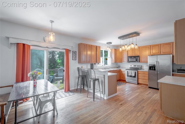 1884 Autumn Glen Dr, Howell, MI 48843 - kitchen featuring appliances with stainless steel finishes, a peninsula, light countertops, and light wood-type flooring