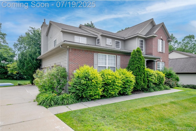 1884 Autumn Glen Dr, Howell, MI 48843 - view of home's exterior with brick siding, a chimney, a yard, and concrete driveway