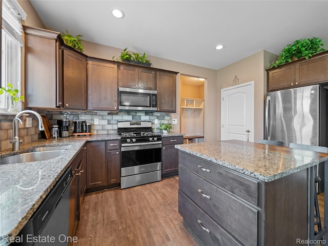 2838 Bogues View Dr, Howell, MI 48843 - kitchen with stainless steel appliances, light wood-type flooring, decorative backsplash, light stone counters, and recessed lighting
