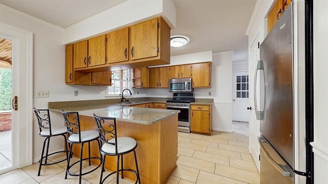 1330 Desmond St, Saint Joseph, MI 49085 - kitchen featuring appliances with stainless steel finishes, a peninsula, brown cabinets, a kitchen bar, and light tile patterned floors