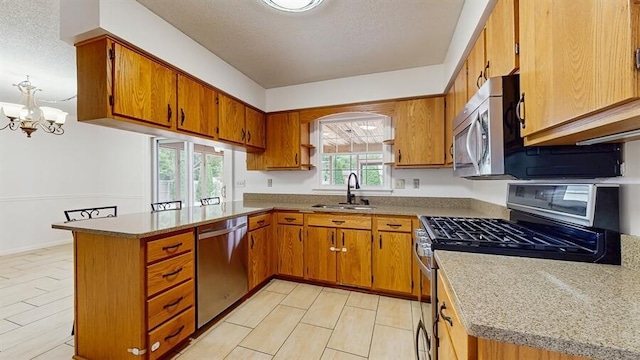 1330 Desmond St, Saint Joseph, MI 49085 - kitchen featuring stainless steel appliances, brown cabinets, a peninsula, a chandelier, and a textured ceiling
