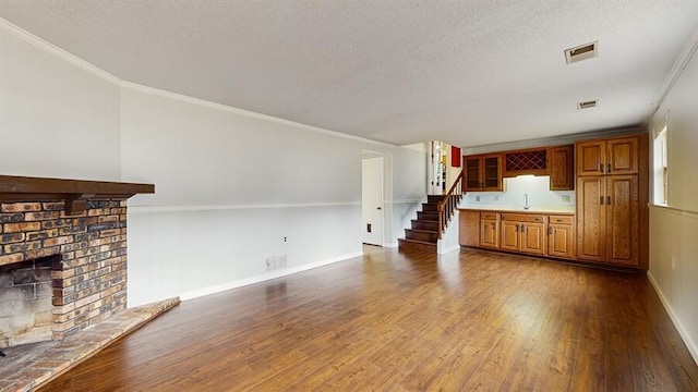 1330 Desmond St, Saint Joseph, MI 49085 - unfurnished living room with wood finished floors, stairway, a textured ceiling, a fireplace, and crown molding
