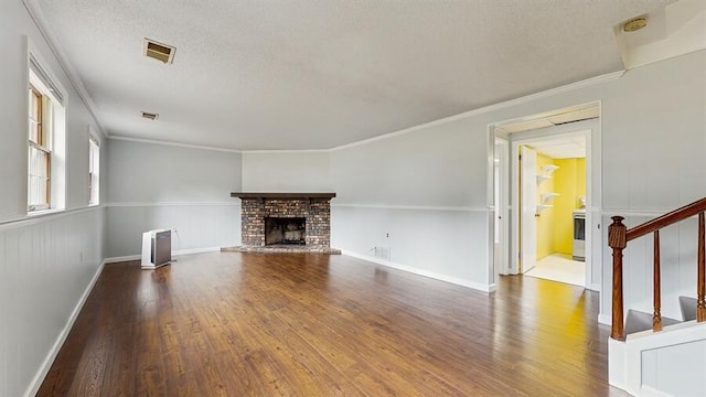 1330 Desmond St, Saint Joseph, MI 49085 - unfurnished living room featuring wood finished floors, a brick fireplace, stairs, a textured ceiling, and crown molding