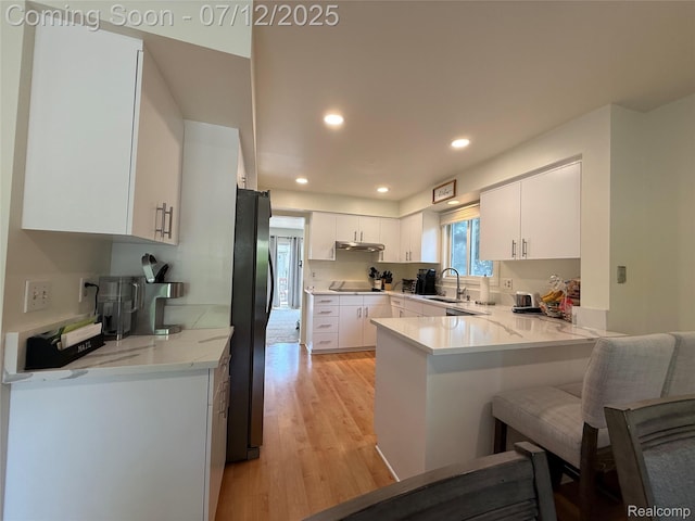 4178 Breckenridge Dr, West Bloomfield, MI 48322 - kitchen with freestanding refrigerator, a peninsula, black electric stovetop, light wood-type flooring, and white cabinetry