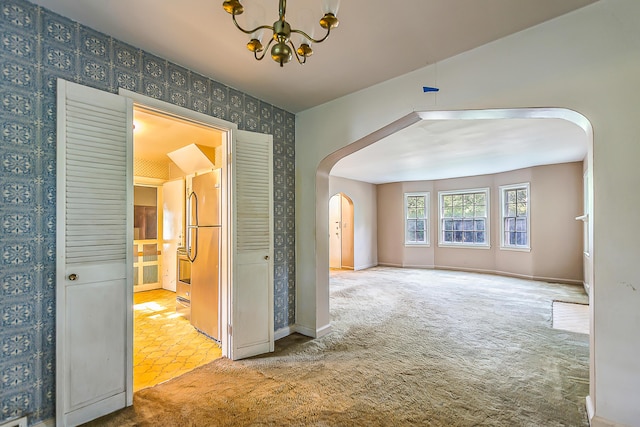 303 Wesley St, Ann Arbor, MI 48103 - spare room featuring arched walkways, wallpapered walls, a chandelier, and carpet floors