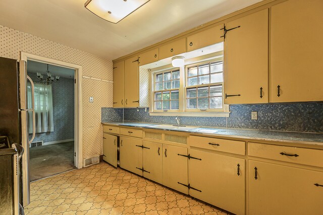 303 Wesley St, Ann Arbor, MI 48103 - kitchen featuring wallpapered walls, a chandelier, backsplash, and freestanding refrigerator