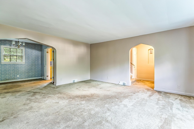 303 Wesley St, Ann Arbor, MI 48103 - empty room featuring arched walkways, carpet, wallpapered walls, stairway, and a chandelier