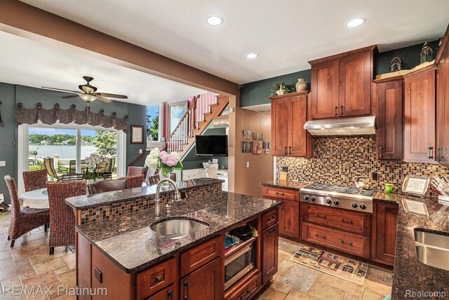 16344 Waterview Ln, Linden, MI 48451 - kitchen featuring stainless steel appliances, under cabinet range hood, stone tile floors, a ceiling fan, and decorative backsplash