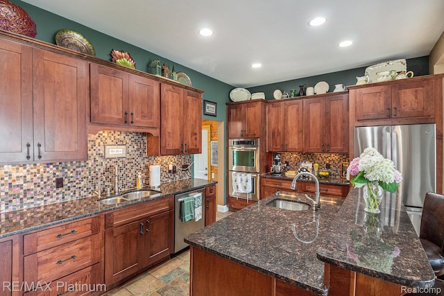 16344 Waterview Ln, Linden, MI 48451 - kitchen with appliances with stainless steel finishes, recessed lighting, backsplash, a center island with sink, and dark stone counters