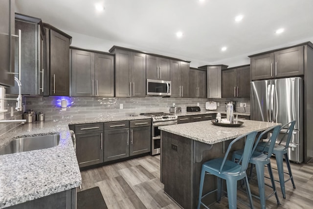 18734 Leonard Ct, New Buffalo, MI 49117 - kitchen with appliances with stainless steel finishes, light stone counters, dark brown cabinetry, a breakfast bar, and decorative backsplash