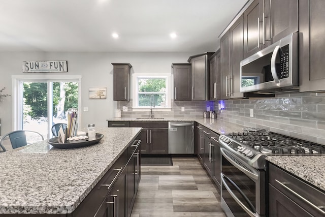 18734 Leonard Ct, New Buffalo, MI 49117 - kitchen featuring appliances with stainless steel finishes, light stone counters, dark brown cabinets, decorative backsplash, and recessed lighting