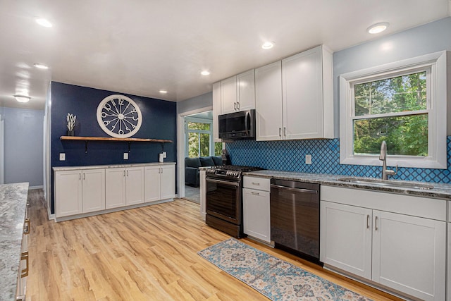 19160 Glendale Cir, Spring Lake, MI 49456 - kitchen featuring appliances with stainless steel finishes, light wood-style floors, decorative backsplash, and white cabinetry