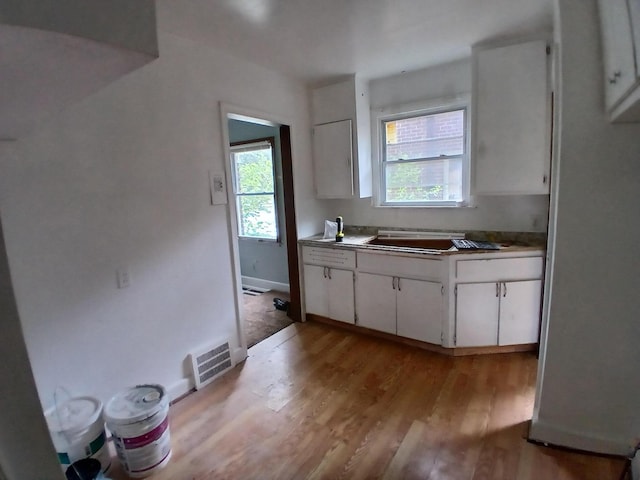 9729 Lakepointe St, Detroit, MI 48224 - kitchen with light wood-type flooring and white cabinetry