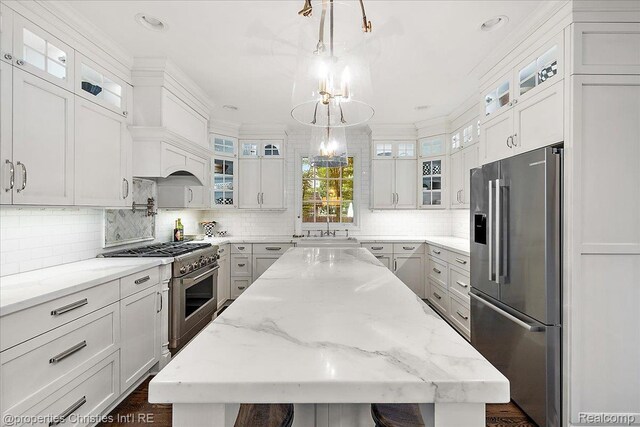 364 Chesterfield Ave, Birmingham, MI 48009 - kitchen featuring high end appliances, a kitchen island, decorative backsplash, a chandelier, and white cabinetry