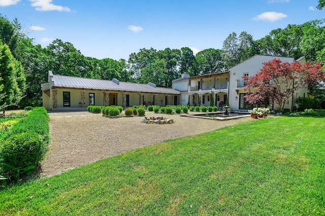 3420 Grange Rd, Berrien Springs, MI 49103 - rear view of property with a yard, stucco siding, a metal roof, driveway, and a chimney