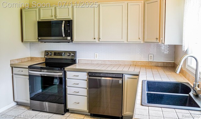 338 N Dr, Davison, MI 48423 - kitchen featuring appliances with stainless steel finishes, tile counters, decorative backsplash, and light tile patterned floors