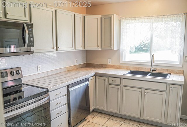 338 N Dr, Davison, MI 48423 - kitchen with appliances with stainless steel finishes, tile counters, decorative backsplash, and light tile patterned floors
