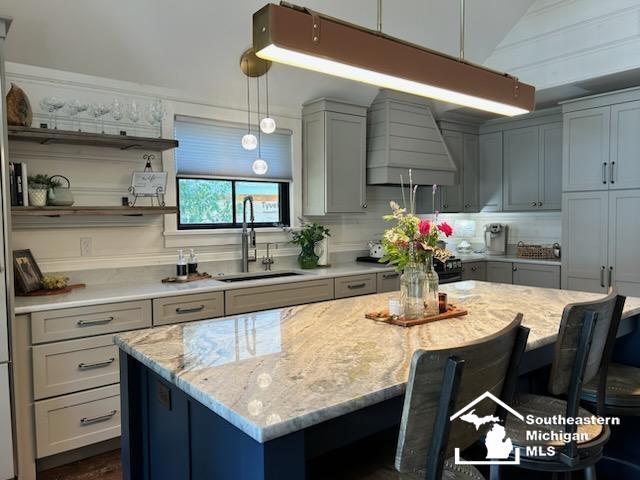 314 W Division St, Boyne City, MI 49712 - kitchen with a breakfast bar area, custom exhaust hood, light stone countertops, a kitchen island, and pendant lighting