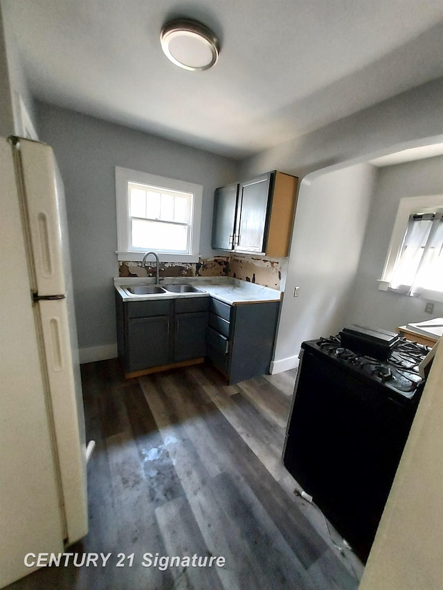 1205 Copeman Blvd, Flint, MI 48504 - kitchen with freestanding refrigerator, stainless steel gas range, dark wood-style flooring, and light countertops
