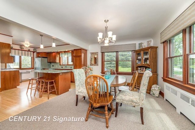 9610 Saginaw St, Reese, MI 48757 - dining space with radiator heating unit, a chandelier, and light wood-type flooring
