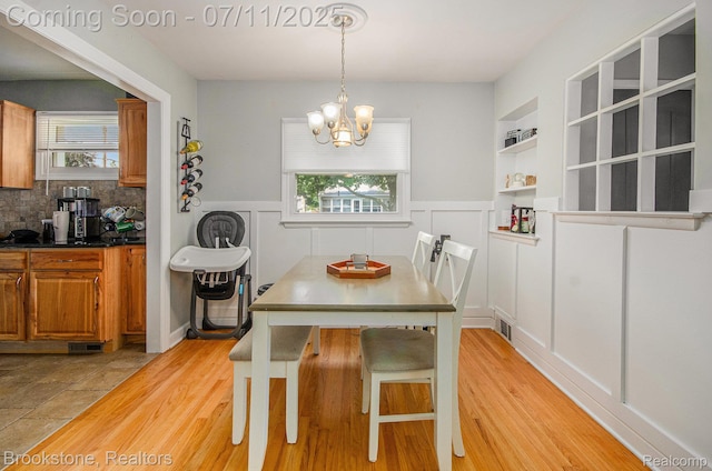 1510 S Harris Rd, Ypsilanti, MI 48198 - dining space featuring a chandelier, healthy amount of natural light, light wood-style flooring, wainscoting, and a decorative wall