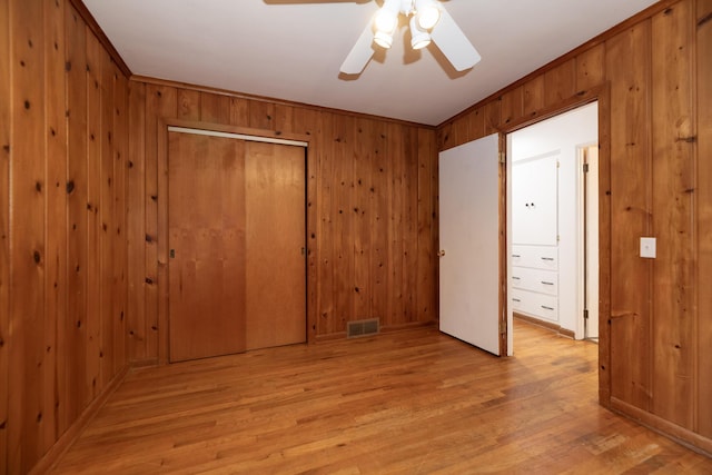 3026 Leigh Ave, Kalamazoo, MI 49048 - unfurnished bedroom with a closet, light wood-style flooring, wood walls, and ceiling fan