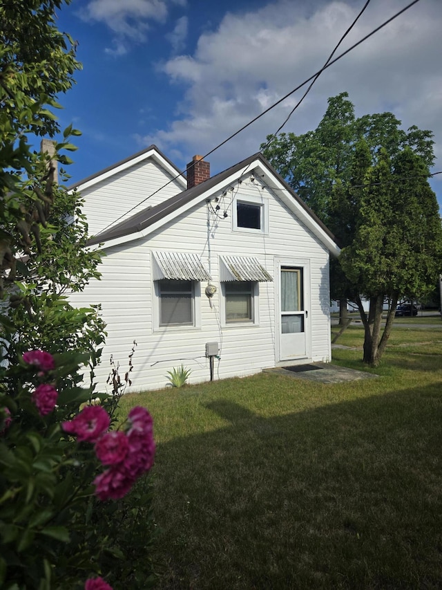 505 N Pine St, Evart, MI 49631 - view of side of home with a chimney and a lawn