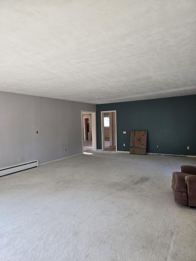 505 N Pine St, Evart, MI 49631 - unfurnished living room featuring a baseboard heating unit and carpet flooring