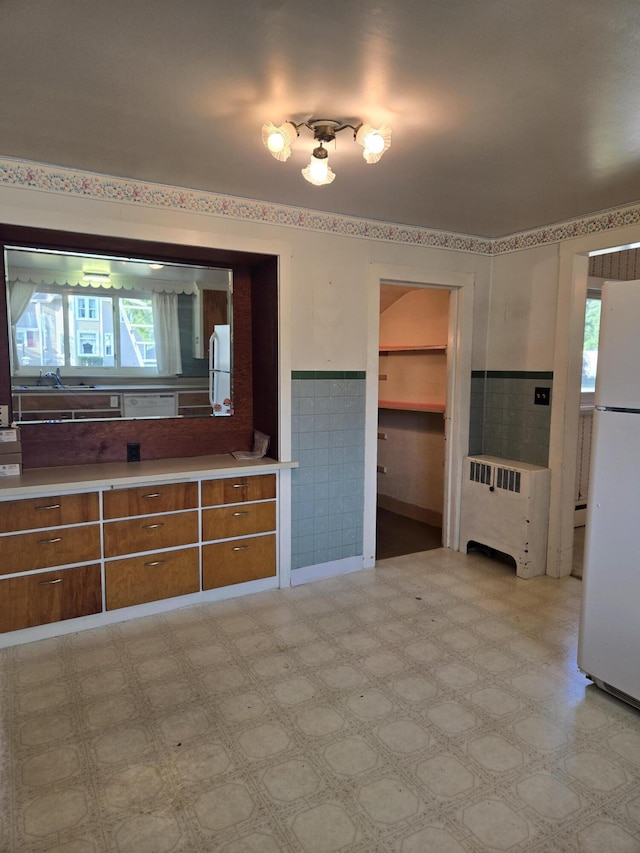 505 N Pine St, Evart, MI 49631 - unfurnished living room featuring radiator, a wainscoted wall, light flooring, and tile walls