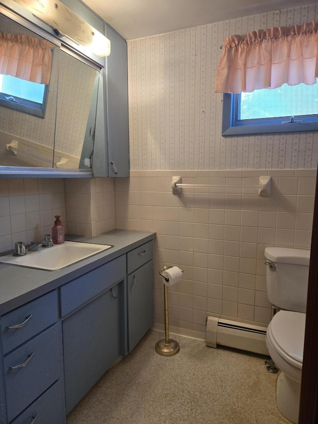 505 N Pine St, Evart, MI 49631 - bathroom with a baseboard heating unit, tile walls, vanity, wallpapered walls, and wainscoting
