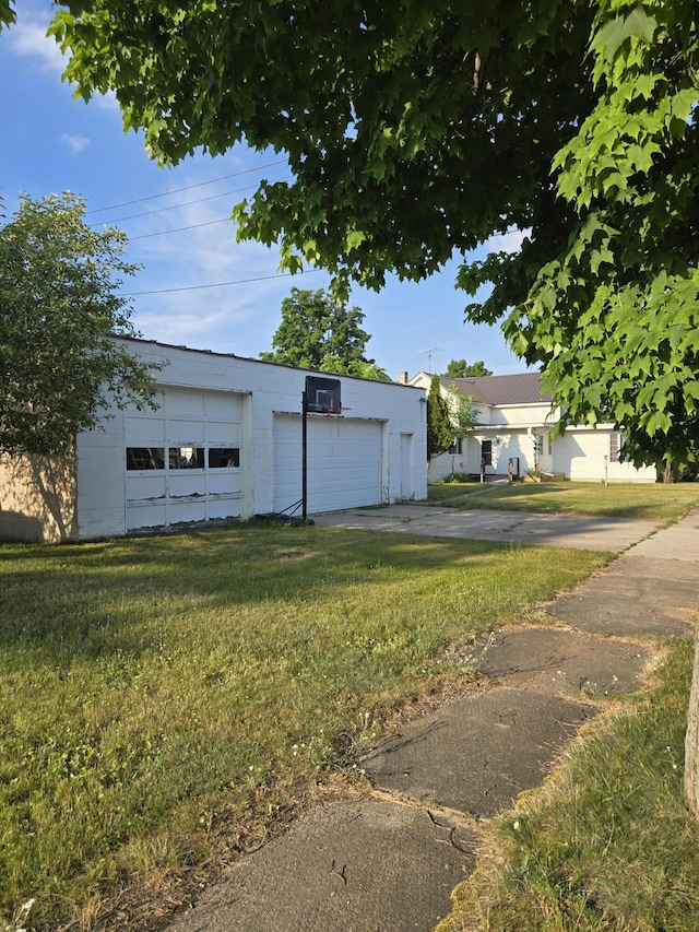 505 N Pine St, Evart, MI 49631 - view of front facade featuring a detached garage, concrete block siding, a front lawn, and an outbuilding