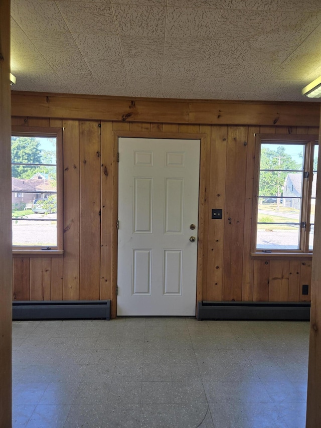505 N Pine St, Evart, MI 49631 - foyer with a baseboard radiator, tile patterned floors, wood walls, and healthy amount of natural light