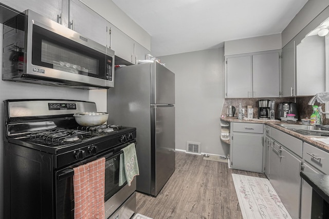 2620 Charlesgate Ave SW, Wyoming, MI 49509 - kitchen with stainless steel appliances, light wood finished floors, decorative backsplash, and gray cabinetry