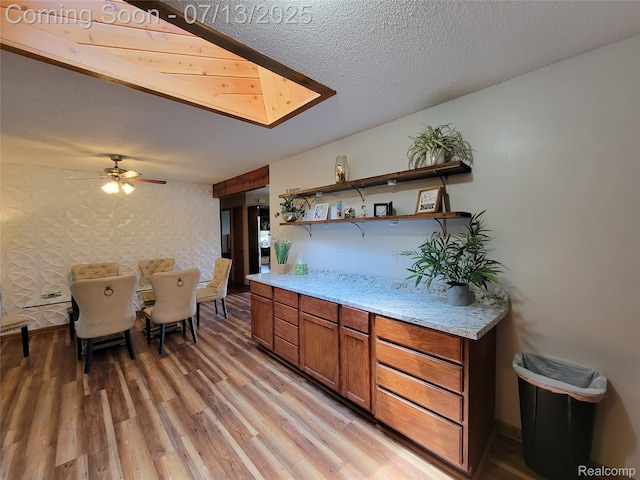 14373 Racho Blvd, Taylor, MI 48180 - kitchen featuring light wood-style flooring, brown cabinetry, open shelves, ceiling fan, and light stone countertops
