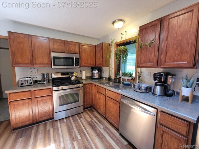 14373 Racho Blvd, Taylor, MI 48180 - kitchen with appliances with stainless steel finishes, light wood-style floors, brown cabinets, tasteful backsplash, and light countertops