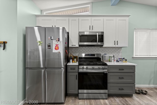 7396 N Charlesworth St, Dearborn Heights, MI 48127 - kitchen featuring stainless steel appliances, gray cabinetry, backsplash, light wood-type flooring, and vaulted ceiling