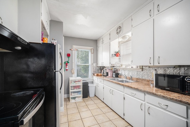 2820 Lowell St, Kalamazoo, MI 49001 - kitchen featuring black appliances, light tile patterned floors, white cabinetry, light countertops, and decorative backsplash