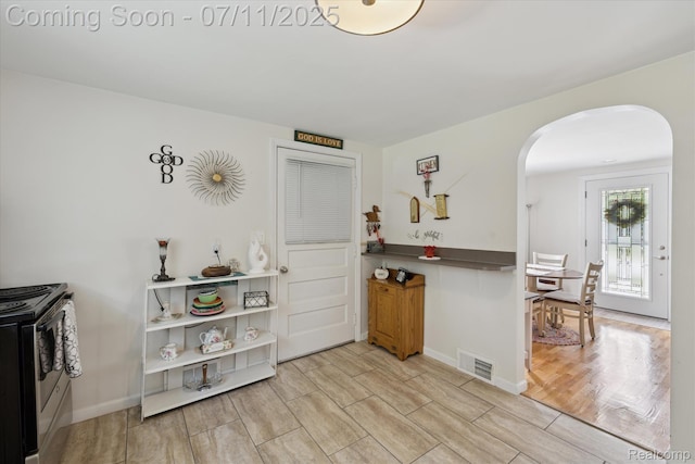 1338 W King St, Owosso, MI 48867 - kitchen with stainless steel gas stove, arched walkways, and light wood finished floors