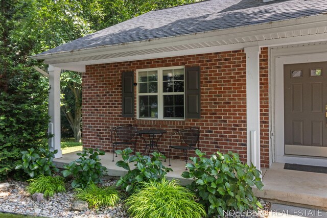 13462 Ravine View Dr, Grand Haven, MI 49417 - doorway to property featuring roof with shingles and brick siding
