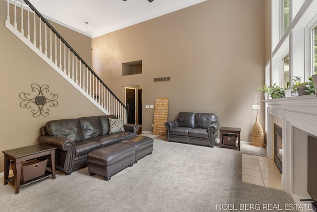 13462 Ravine View Dr, Grand Haven, MI 49417 - living area with carpet, a high ceiling, stairway, a fireplace with flush hearth, and ornamental molding