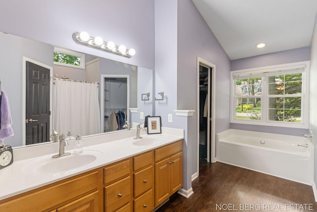 13462 Ravine View Dr, Grand Haven, MI 49417 - full bathroom with double vanity, wood finished floors, a garden tub, a spacious closet, and vaulted ceiling