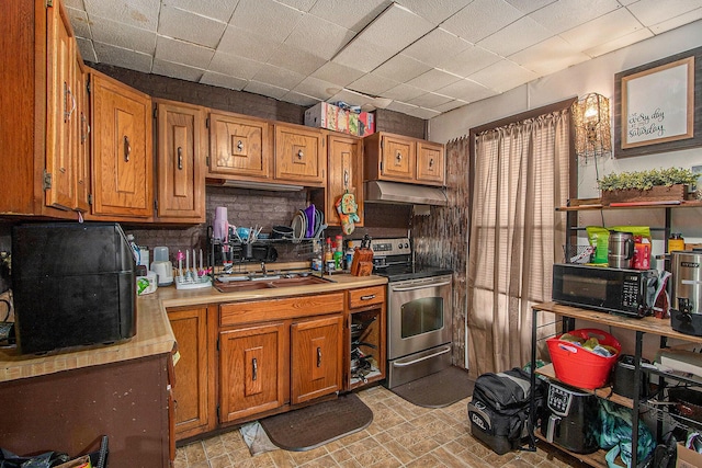 54 Wren St, Battle Creek, MI 49017 - kitchen featuring black microwave, stainless steel range with electric cooktop, light countertops, under cabinet range hood, and brown cabinetry